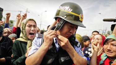 Mass unrest … Uighur women surround a Chinese riot policeman during protests in Urumchi, the capital of Xinjiang province, last July.