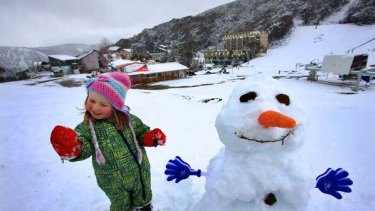Two-year-old Emma Hocking stands beside a snowman at Falls Creek.