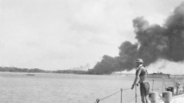 A ship burns in the port of Darwin after raids by Japanese bombers.