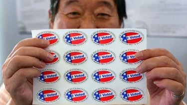 Election official Henry Tung displays a sheet of "I Voted" stickers in Monterey Park, Los Angeles.