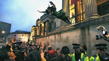 Elated: A reveller who had climbed onto a ledge outside the National Gallery leaps into the crowd during the outdoor party.