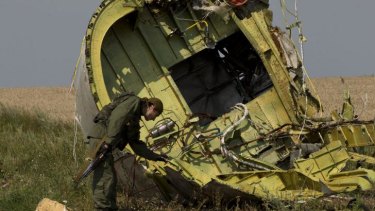 A pro-Russian rebel touches the MH17 wreckage at the crash site of Malaysia Airlines Flight 17, in eastern Ukraine.