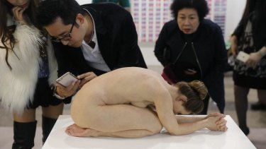 Visitors take photos of  <i>Untitled (Kneeling Woman)</i> by Australian artist Sam Jinks during this year's Art Basel in Hong Kong.