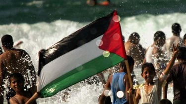 "There is also a sense of foreboding" ... Palestinian children hold the national flag as bathers enjoy the Mediterranean sea next to the Mawasi area in the Gaza Strip.