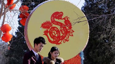 A couple walks past a decorative drum with a paper-cutting of a snake ahead of the Chinese Lunar New Year celebrations in Beijing.