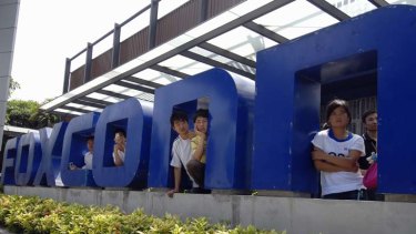 Workers stand at the gate of a Foxconn factory in Shenzhen, where Apple has faced criticism over alleged abuse.