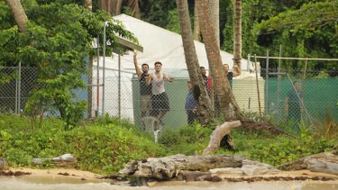Asylum seekers wave from behind the wire of the Manus Island detention centre in Papua New Guinea.