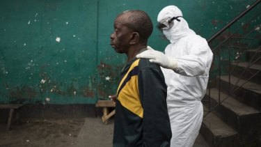 Careful approach: A health worker with a man who is suspected of being infected with Ebola.