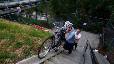 Fuming: Australian Cyclists Party Richard Bowen (white top) and Troy Parsons with his son Denali at the steps on the end of Gipps Street in Collingwood which governments have promised to fix. 