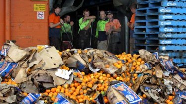 Clean-up begins ... Brisbane Markets employees at Quality Fruits start the removal of toinnes of fruit and vegetables destroyed by the floodwaters that reached to the roofs of warehouses.