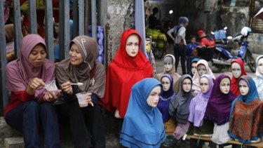 Fashion: Girls sit near mannequins displaying hijabs for sale at Tanah Abang market in Jakarta.