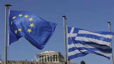 The EU and Greek flags wave under the ancient Acropolis hill in Athens.