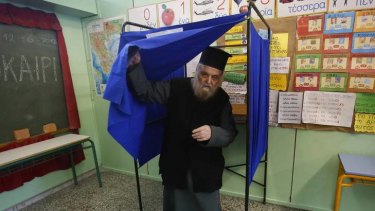 A Greek Orthodox priest leaves a voting booth at a primary school in Athens.