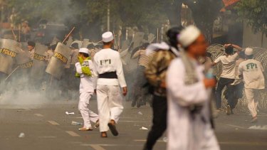 Men throw rocks as Indonesian police release tear gas at anti-American protests in front of the United States embassy in Jakarta.
