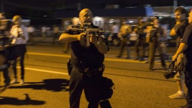 Missouri police officer Ray Albers points an assault rifle at a protester.