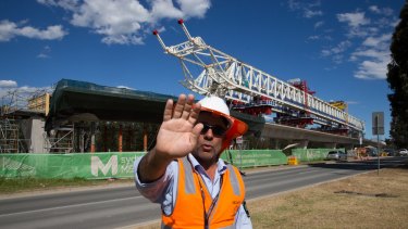A security guard attempts to stop photographs of the buckled span on the Skytrain viaduct in Sydney's north-west.