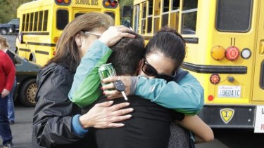 Parents embrace in front of school buses after the shooting at Marysville Pilchuck High School.