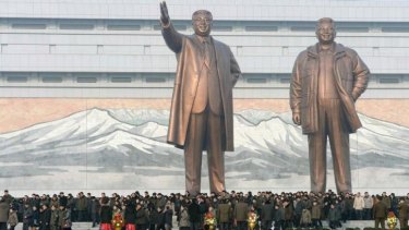 North Koreans gather in front of bronze statues of North Korea's founder Kim Il Sung.