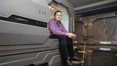 James Oliver, manager of the Capsule Hotel, sits in one of the capsules.