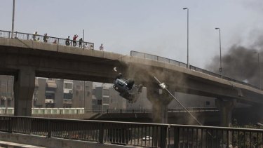 A police vehicle is pushed off of the 6th of October bridge by protesters.