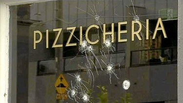 Bullet holes pierce the window of the Woodstock Pizzicheria on Lygon Street in October 2013.