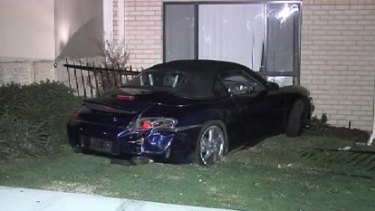 The damaged Porsche sits on the front garden of the Belmont house.