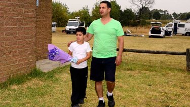 Wally Rachid with his son, Jad, with flowers at the Tyabb football club. Jad, nearly 11, knew Luke Batty.