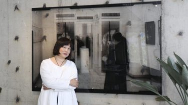 Xiao Lu in her Beijing studio, with an image of her firing her gun at China's National Art Museum in February 1989.