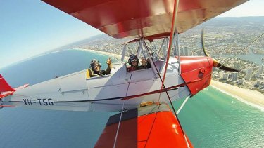Pilot Alex James "Jim" Rae, 26, and his wife Alice fly a Tiger Moth over the Gold Coast.