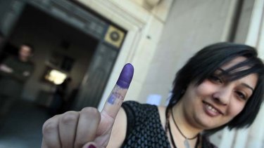 A Syrian woman shows her ink dipped finger after casting her vote in the parliamentary elections at a polling station in Damascus.