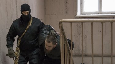 Police drag Tamerlan Eskerkhanov, one of five 'suspects' in the killing of Boris Nemtsov up the stairs of the court building on Sunday.