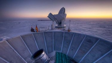 The sun sets behind the BICEP2 telescope and the South Pole telescope in Antarctica.