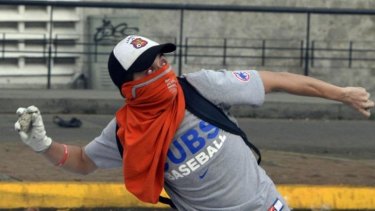 A Venezuelan anti-government student throws stones at riot police during a protest in Valencia.