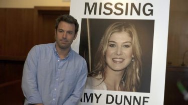 Ben Affleck in <i>Gone Girl</i> with a poster of his missing wife played by Rosamund Pike.