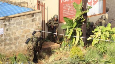 Kenya Defence Force soldiers take cover behind walls near the Westgate shopping centre  in Nairobi after an exchange of gunfire inside the mall.