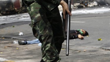 Fight to the death...a soldier walks past a body in Bangkok as troops moved in to end the anti-government protest.
