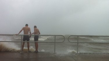 Teenage boys stand on the ocean-front guard rail at Brighton in Queensland waiting for waves to break on top if them.