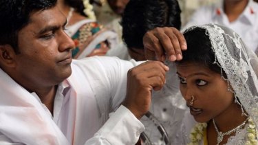 A groom adjusts the hairpin of his bride during a multi-faith mass wedding in Mumbai last month. 