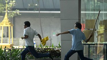 A man with yellow cloth — which symbolises opposition to the Government — is pursued at Bangkok's main airport.