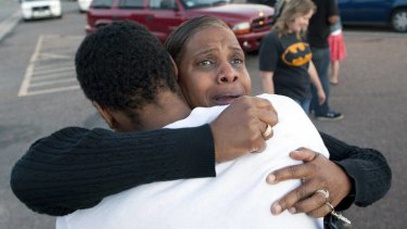 Shamecca Davis hugs her son Isaiah Bow, who was a witness to the shooting, outside Gateway High School where film-goers were brought for questioning.