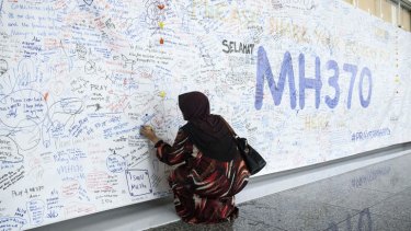 Outpouring of emotion ... A woman writes a message on a banner for passengers of missing Malaysian Airlines Flight 370 at Kuala Lumpur International Airport (KLIA) in Sepang, Malaysia.