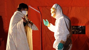 An official in protective gear talks to a woman evacuated from the area near the Fukushima Daini nuclear plant.