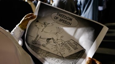 A Muslim holds a cartoon during a rally to show their support for the Prophet Muhammad in Lakemba on Friday.