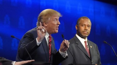 Quite the competition: Ben Carson, right, watches as Donald Trump speaks during a debate. 