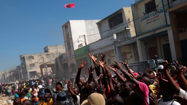 Looting ... Haitians reach out as goods are thrown from a shop.