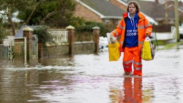 A man walks through flooded streets in the village of Moorland in Somerset, England.