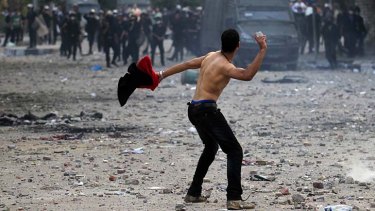 A demonstrator throws a stone towards police.