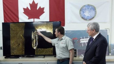 Canada's Prime Minister Stephen Harper (right) listens as Parks Canada's Ryan Harris talks about an image showing one of two ships from the lost Franklin expedition, in Ottawa.