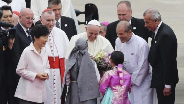 The Pope greets South Korean children at Seoul Air Base as Park Geun-hye (left) looks on.