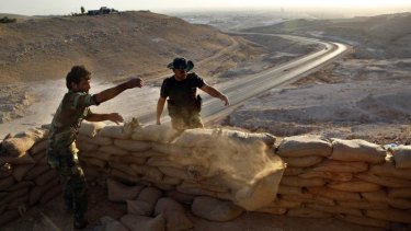 Peshmerga fighters pile up sandbags to make a gun placement on the road to Makhmur.